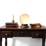 Een vintage houten bureau met een kristallen bal en oude boeken.